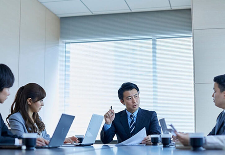 会議室で資料を手に話し合うビジネスパーソンたち