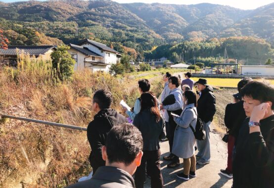 山あいの住宅地で現地見学会に参加し、周辺環境を確認する人たち
